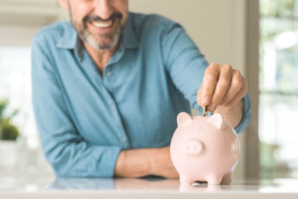 Mann wirft Geld in Sparschwein