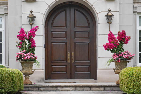 zweiflügelige Haustür aus dunklem Holz mit Rundbogen