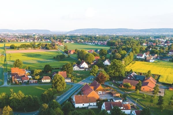 Luftaufnahme einer Ortschaft in Deutschland mit Wiesen bei Sonnenschein