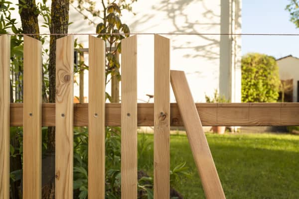 Im Bau befindlicher Zaun aus Holz mit Holzlatten, von denen einige bereits befestigt sind