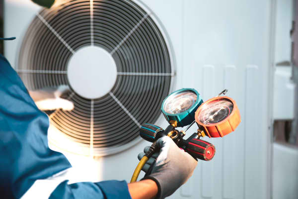 Mechaniker überprüft Kältemittel in einer Wärmepumpe mit einem Manometer