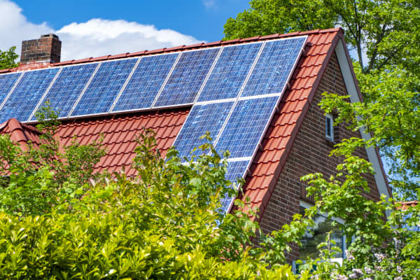 Sonnenkollektoren auf einem roten Giebeldach bei Sonnenschein