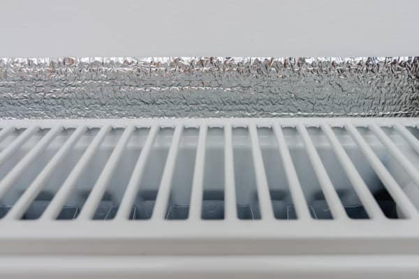 Nahaufnahme eines Heizkörpers, hinter dem eine silberne Dämmfolie angebracht ist