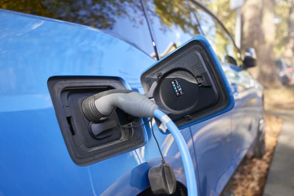 Nahaufnahme eines blauen E-Autos, das gerade geladen wird