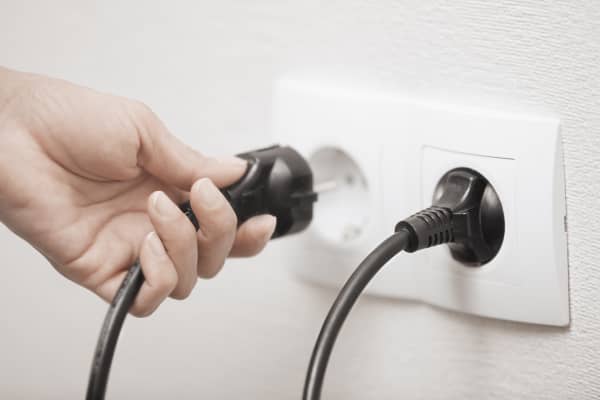Frau steckt einen Stecker in eine Steckdose, Nahaufnahme ihrer Hand