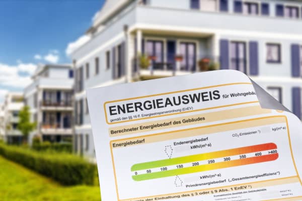 Energieausweis mit modernem Mehrfamilienhaus im Hintergrund