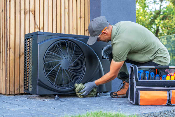 Monteur arbeitet im Freien an einer schwarzen Wärmepumpe