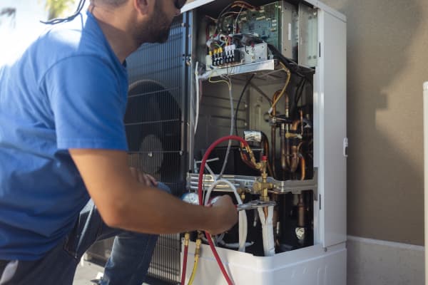 Handwerker arbeitet an der Elektrik einer Wärmepumpe