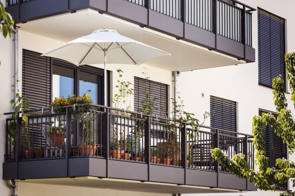 Balkon mit Pflanzen und Sonnenschirm an einem modernen Mehrfamilienhaus