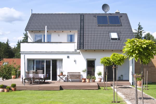 Weißes freistehendes Einfamilienhaus mit Terrasse im Grünen