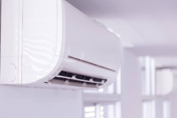 Nahansicht des Innengeräts einer fest installierten Klimaanlage in einem Raum mit weißen Wänden