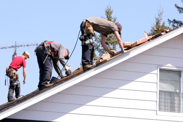 Drei Handwerker machen eine energetische Sanierung auf einem Hausdach
