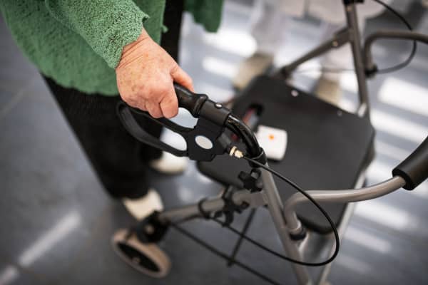 Seniorin in schwarzer Hose und grünem Oberteil mit einem Rollator