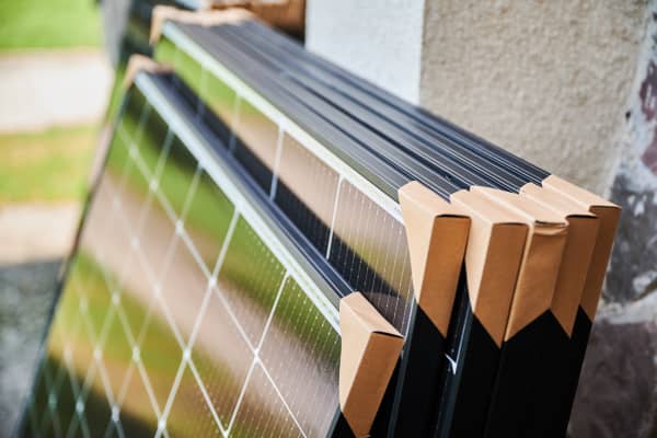 Mehrere verpackte Solarmodule lehnen am Äußeren eines Gebäudes