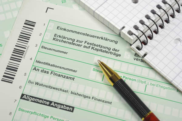 Formulare zur Einkommensteuererklärung mit Notizblock und Kugelschreiber