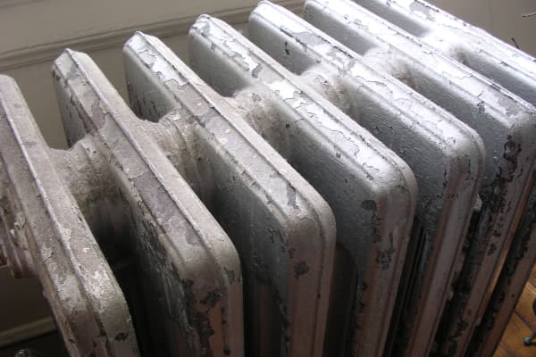 Alter Gliederheizkörper mit abgeplatzter Farbe in einem Wohnraum