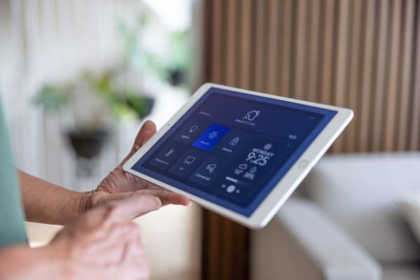Ältere Person hält ein Tablet mit Smart-Home-Anwendung