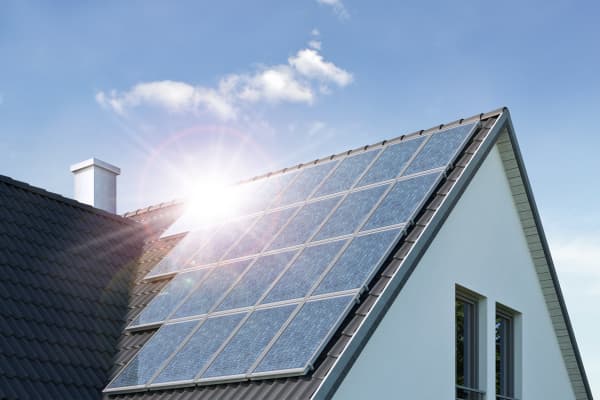 Sonne spiegelt sich in Solarmodulen auf dem Dach eines Wohnhauses