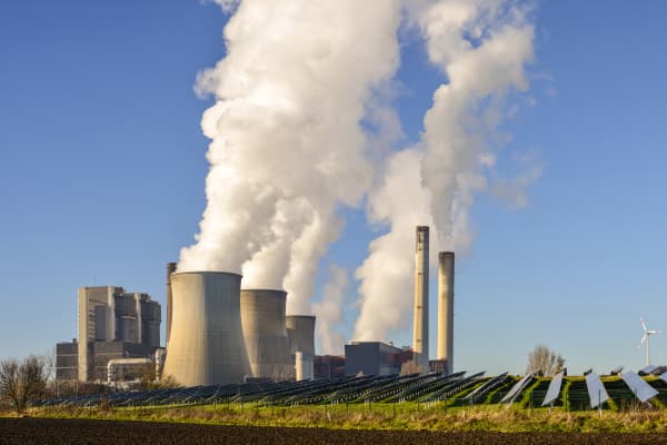 Kohlekraftwerk, Solar und Windräder vor blauem Himmel