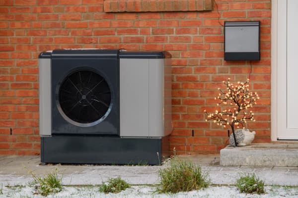 Wärmepumpe neben Eingang eines Altbaus aus rotem Backstein