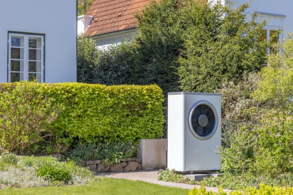 Wärmepumpe im Garten vor einem Haus im Grünen