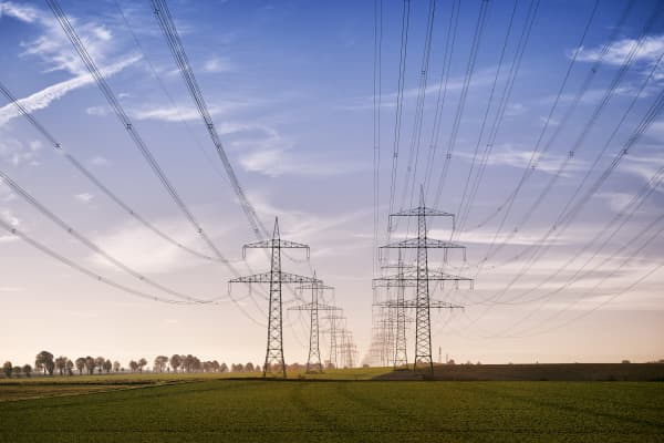 Strommasten in zwei Reihen bei Sonnenaufgang