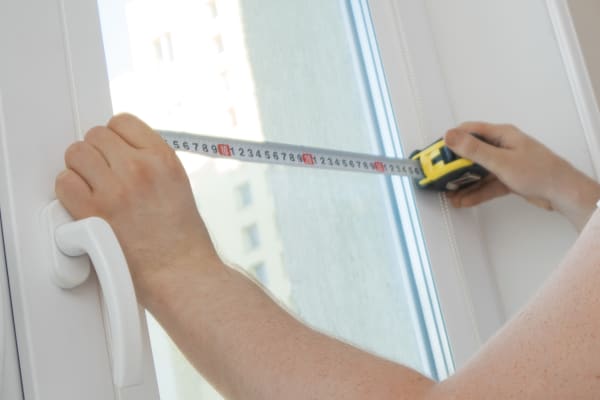 Fenstermessung mit Maßband – Hände messen Fensterbreite