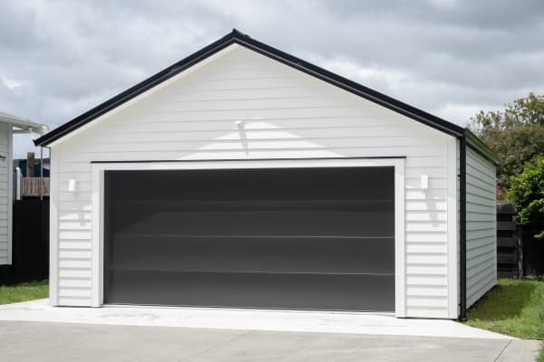 Weiße Holzgarage mit Garagentor für zwei Autos