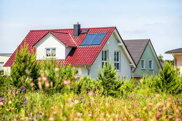 Ansicht auf zwei freistehende Einfamilienhäuser von einer Wiese aus