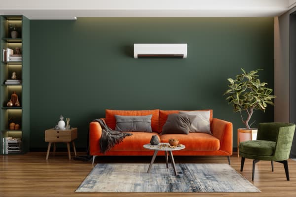 Modernes Wohnzimmer mit grünen Wänden, Klimaanlage, orangefarbenem Sofa und grünem Sessel