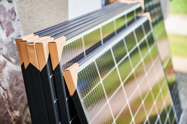 Mehrere verpackte Solarmodule lehnen an einer Hauswand
