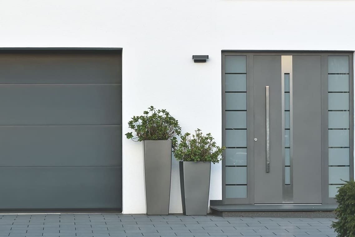 Ans Haus gebaute Garage mit Garagentor neben Hauseingang