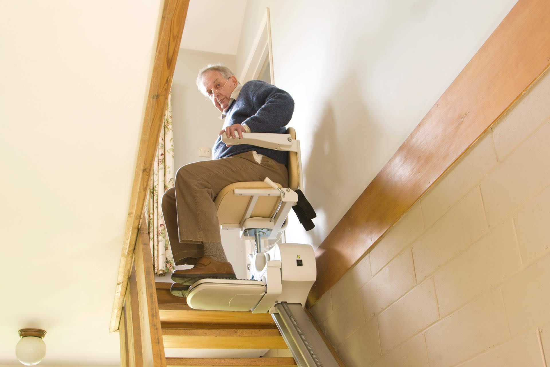 Mann nutzt einen platzsparenden Treppenlift auf einer schmalen Treppe.
