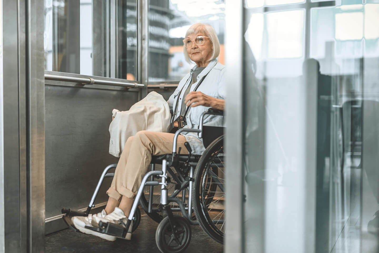 Ältere Frau im Rollstuhl im Fahrstuhl