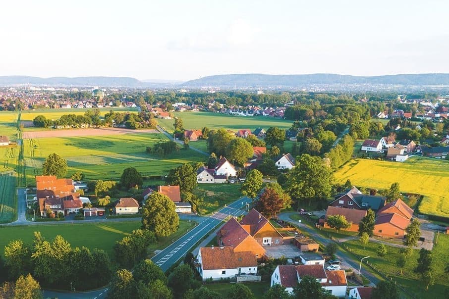 Luftaufnahme einer Ortschaft in Deutschland mit Wiesen bei Sonnenschein