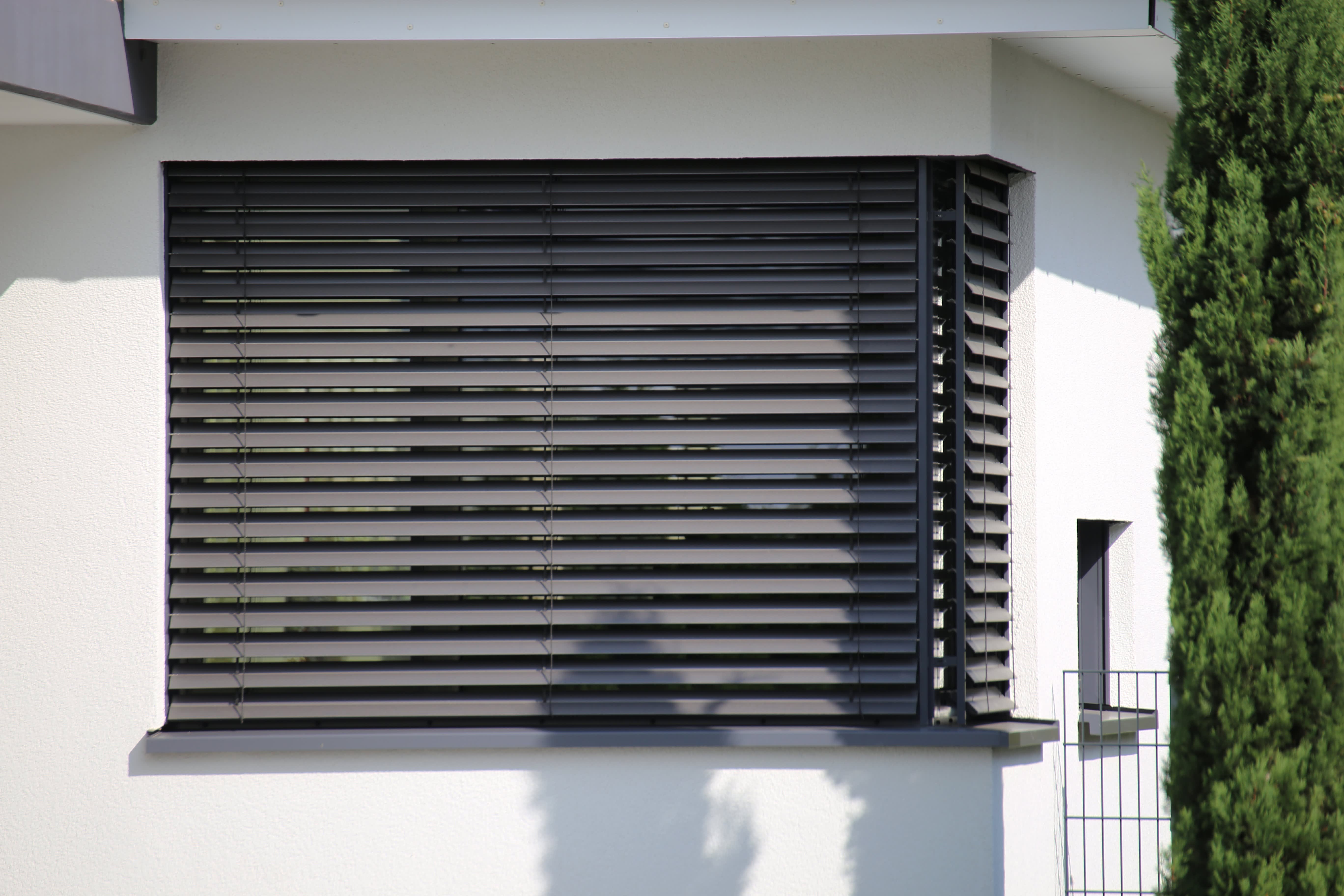 Das Bild zeigt moderne Rollladen an einem Fenster eines weißen Hauses