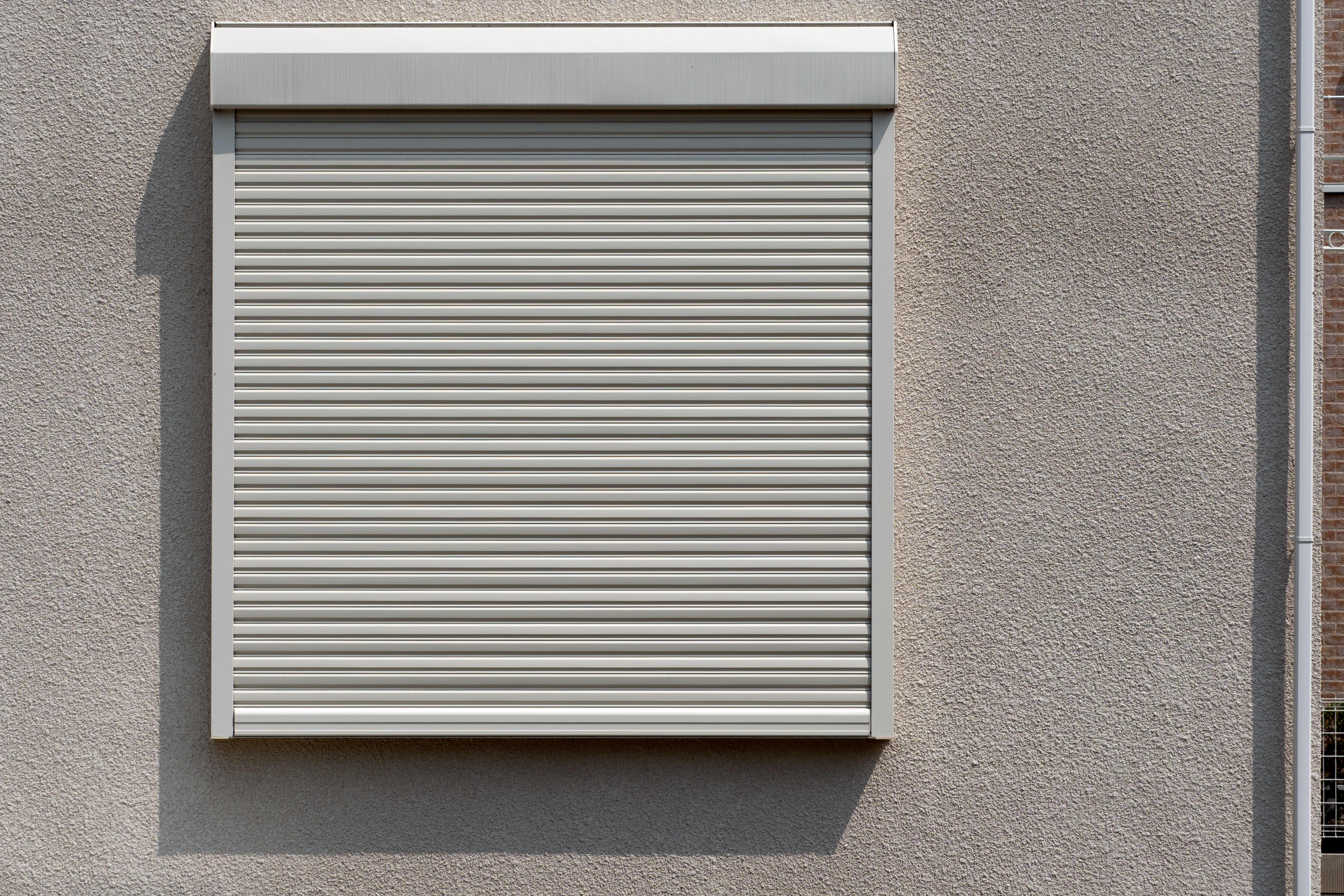 Ein geschlossener Rollladen aus Kunststoff von außen an einem Fenster.