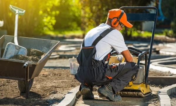 Handwerker bereitet Pflasterung eines Gartenwegs vor.