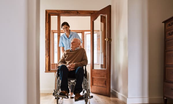 Junge Frau schiebt älteren Mann im Rollstuhl