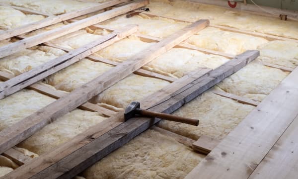 Holzdielen auf Glaswolle, auf denen ein Hammer liegt