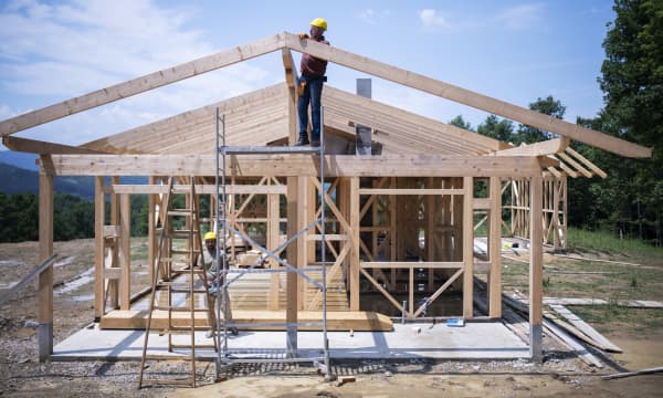 Bauarbeiter arbeiten auf Baustelle eines modernen Holzhauses
