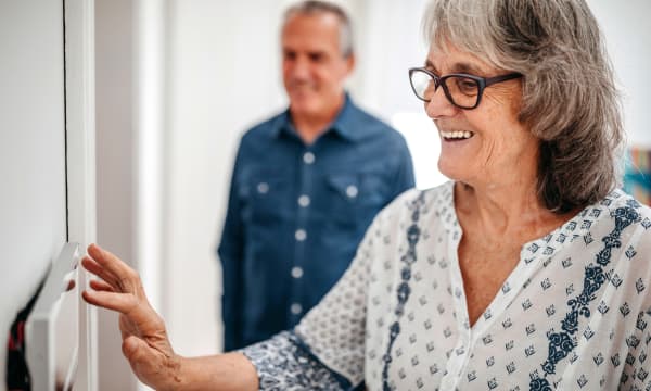 Lächelnde Seniorin stellt ihren digitalen Heizungsregler ein