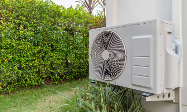 Wärmepumpe am Haus neben Hecke zum Nachbargrundstück