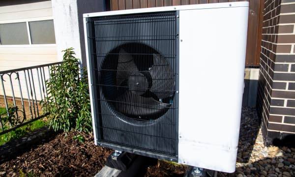 Weiße Luft-Wasser-Wärmepumpe vor Einfamilienhaus