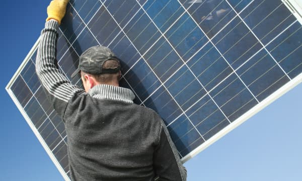 Handwerker trägt ein Solarmodul zur Installation einer Photovoltaikanlage