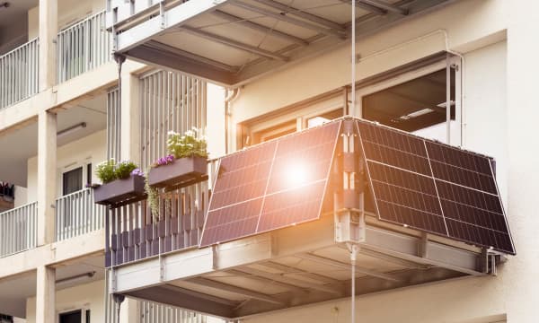 Balkon mit Balkonkraftwerk, dessen Module das Sonnenlicht reflektieren