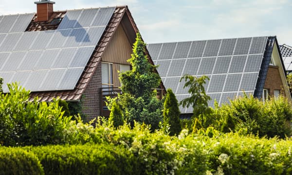Zwei Wohnhäuser mit Solaranlagen auf den Dächern im Grünen