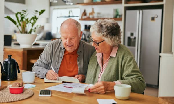Älteres Paar sitzt am Küchentisch über Rechnungen
