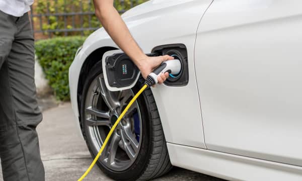 Mann lädt sein Elektroauto vor seinem Haus