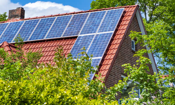 Sonnenkollektoren auf einem roten Giebeldach bei Sonnenschein